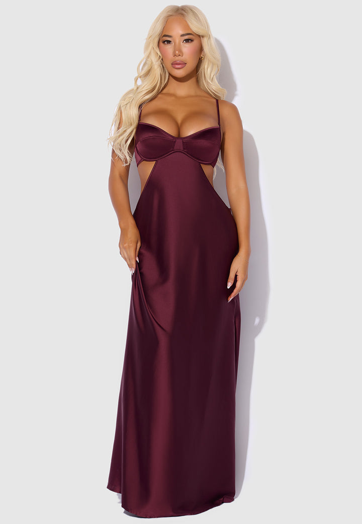 Woman wearing a burgundy evening gown with cut-out design on a white background