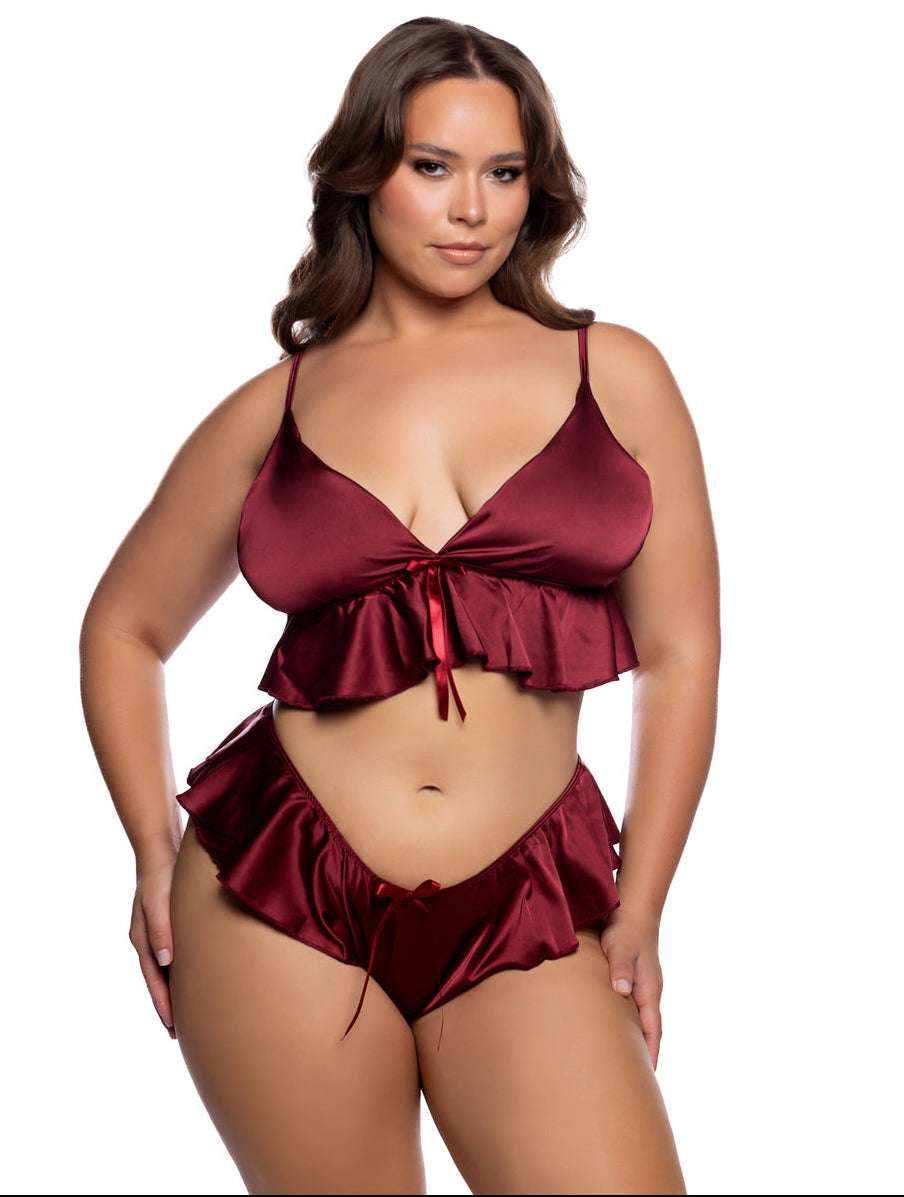 A plus size lingerie model in a two-piece satin lingerie set in deep burgundy, featuring a ruffled crop top and matching high-cut bottoms, against a solid white background.