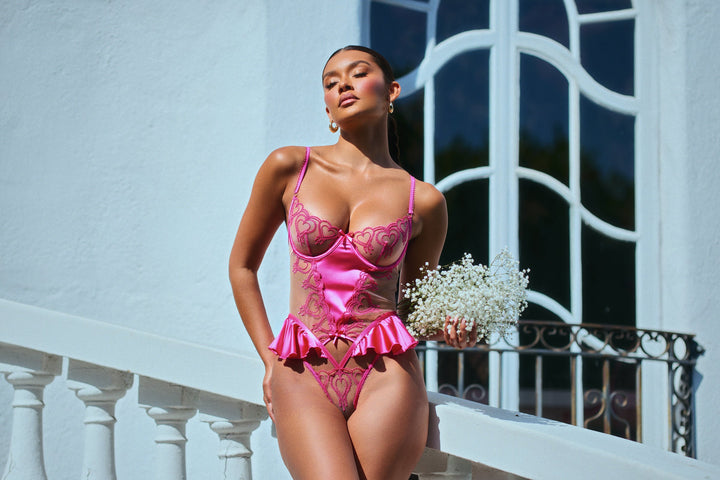 Model wearing a pink women's teddy with hearts design for Valentine's Day.