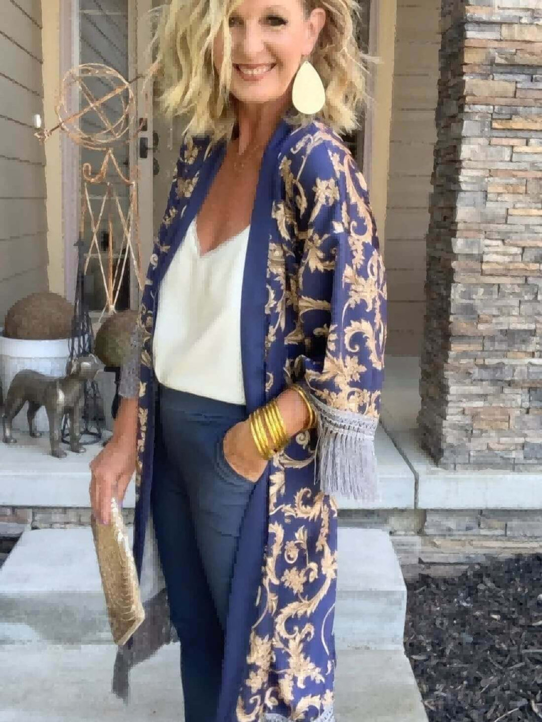 A woman wearing a Tassels Blue Kimono Robe, embodying luxury and elegance, styled with accessories and elegant pants.