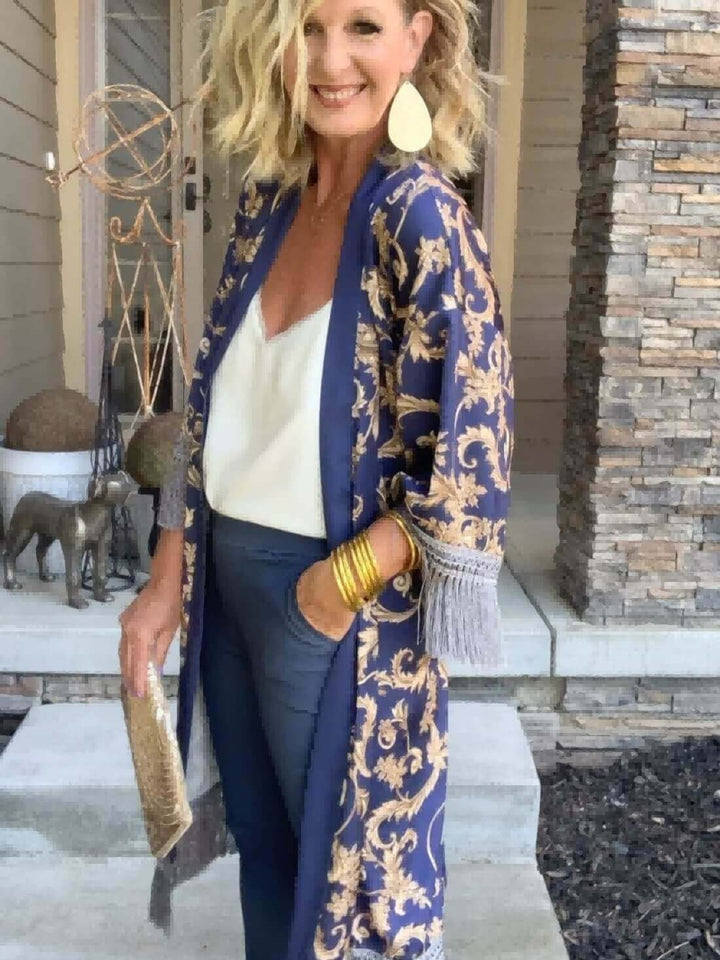 A woman wearing a Tassels Blue Kimono Robe, embodying luxury and elegance, styled with accessories and elegant pants.