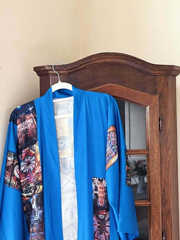 Paris Cathedral Kimono Robe displayed on a hanger against a wooden cabinet, showcasing its vibrant colors and intricate design.