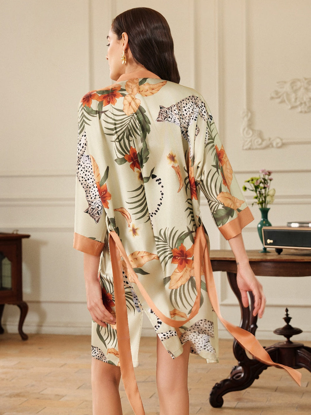 Woman wearing an Orange Leopard Short Kimono Robe, showcasing its vibrant floral and leopard print design.