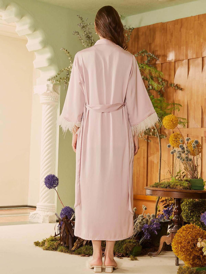 Back view of a woman in a luxurious Pink Feather Bridal Robe, showcasing its elegance and silky design.