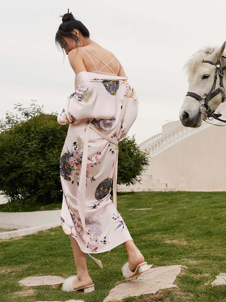 Woman wearing Garden Crane Blush Kimono Robe in a garden with a horse, showcasing luxury and elegance.