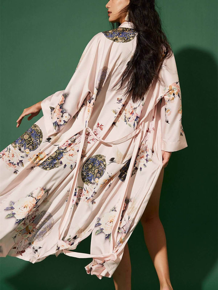 Woman wearing a Garden Crane Blush Kimono Robe with floral prints, showcasing luxury and elegance.
