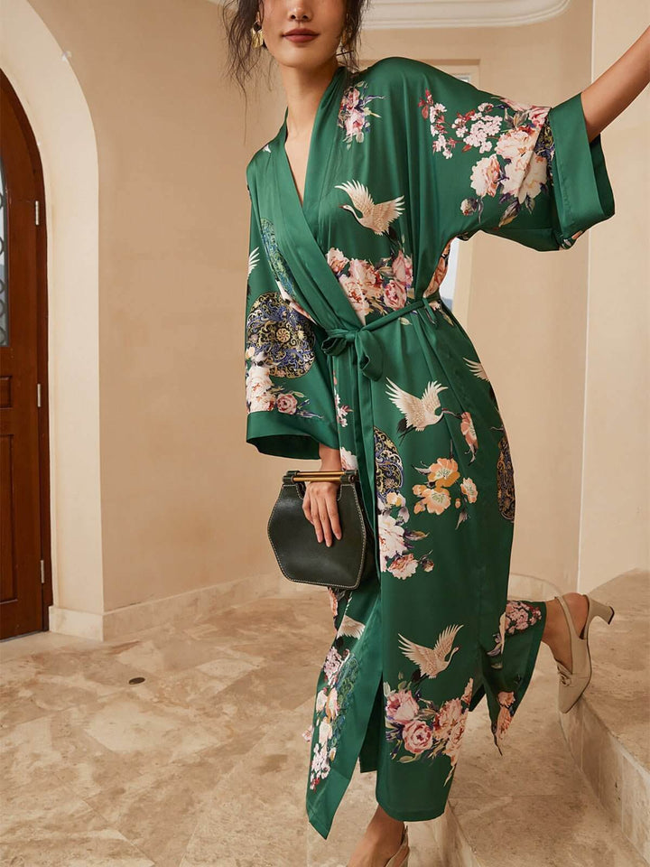 Woman in a Garden Crane Green Kimono Robe, showcasing luxury with floral patterns in a stylish setting.