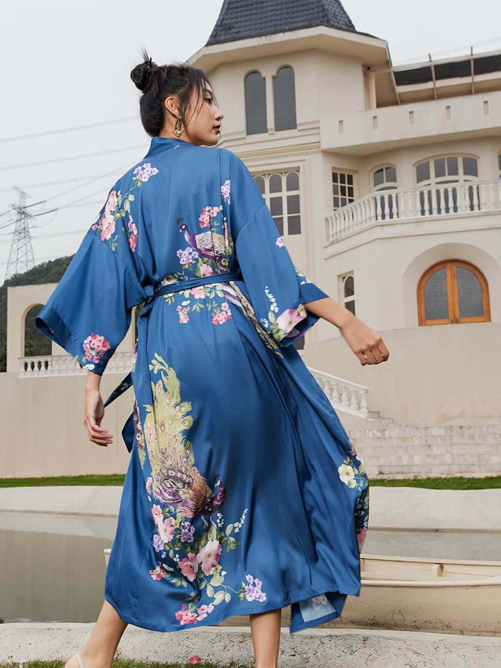 Model showcasing a stylish Peacock Blue Kimono Robe with floral prints in a luxurious setting.