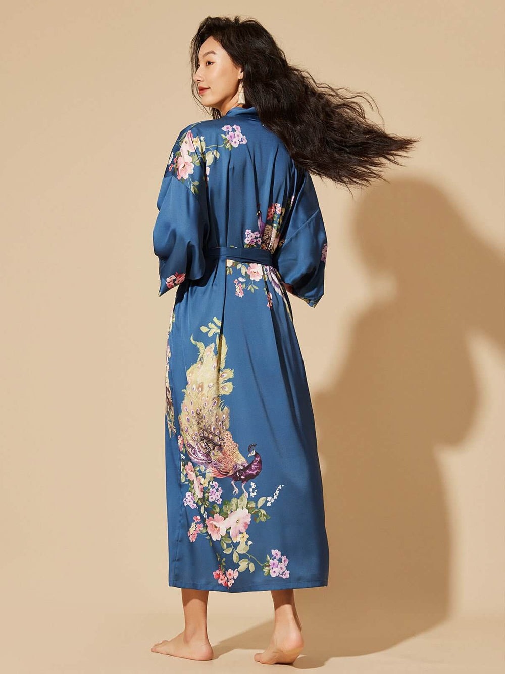 Woman wearing a Peacock Blue Kimono Robe with floral prints, showcasing luxury and elegance.