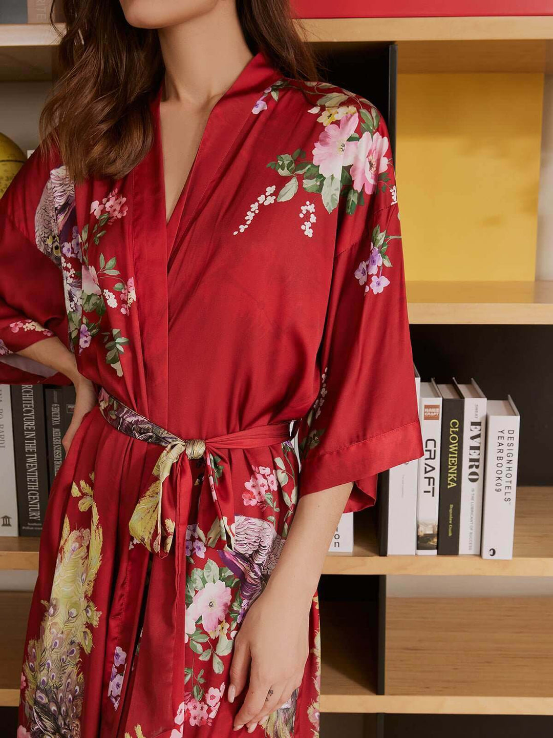 Model wearing a Peacock Red Kimono Robe with floral patterns, showcasing luxury and comfort in a chic setting.