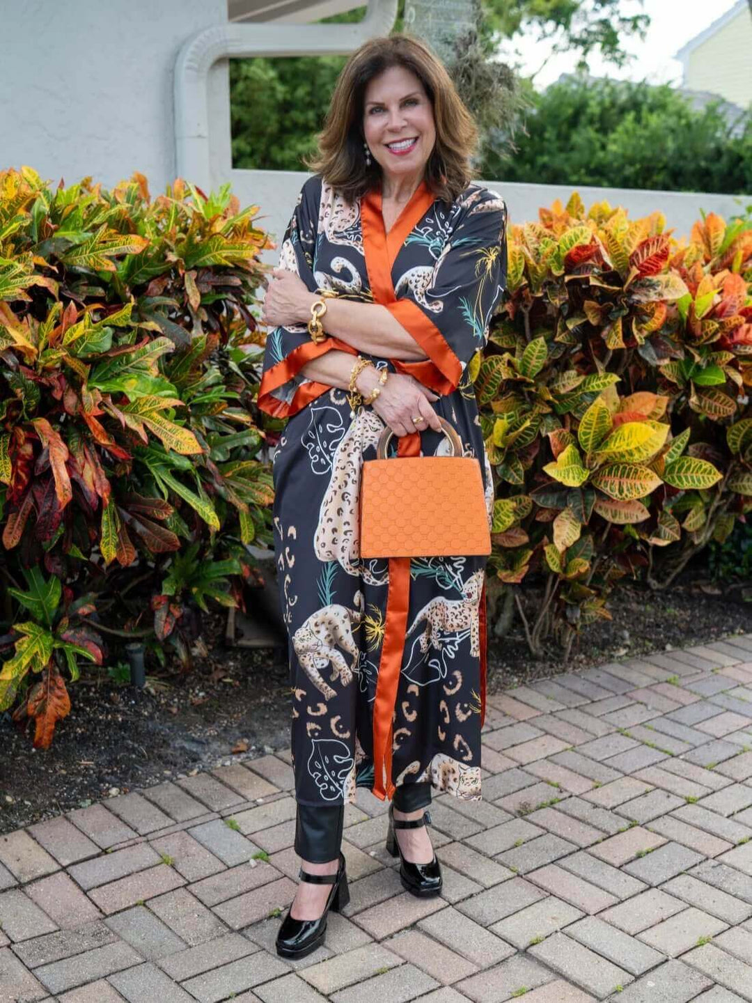 Woman wearing a Jungle Animals Kimono Robe with vibrant colors, posing in a tropical garden.
