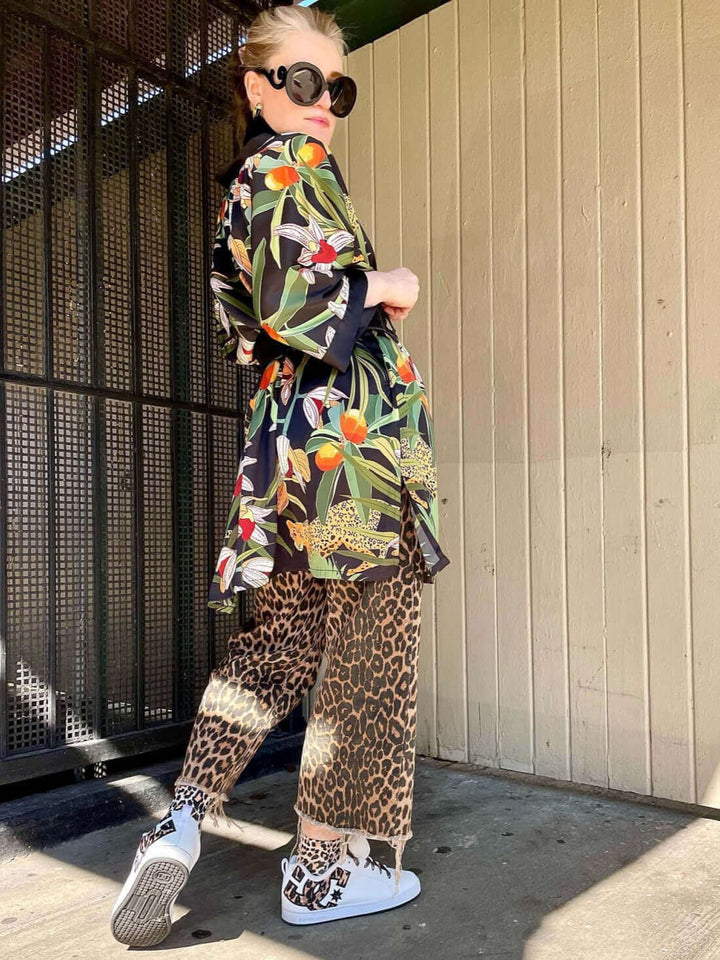 Model showcasing a Short Kimono Robe Black Leopard with stylish pants and accessories in an outdoor setting.