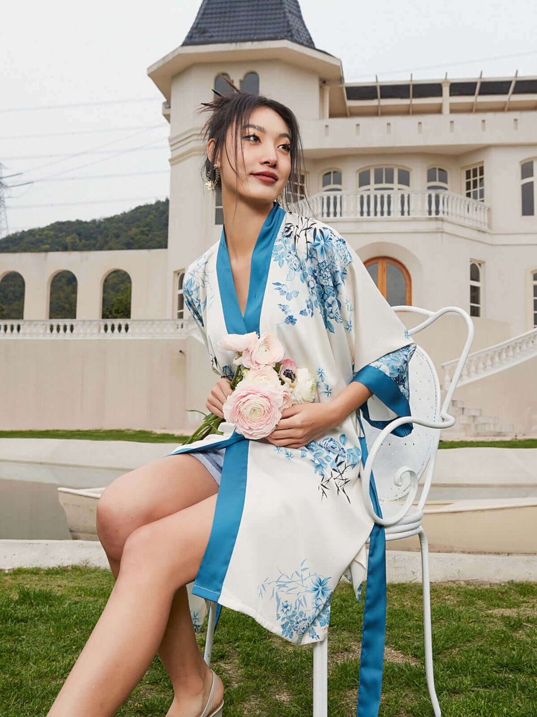 Short Kimono Robe bamboo worn by a woman sitting outdoors, holding flowers, showcasing elegance and luxury.